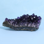 Amethyst crystal cluster on a light blue background