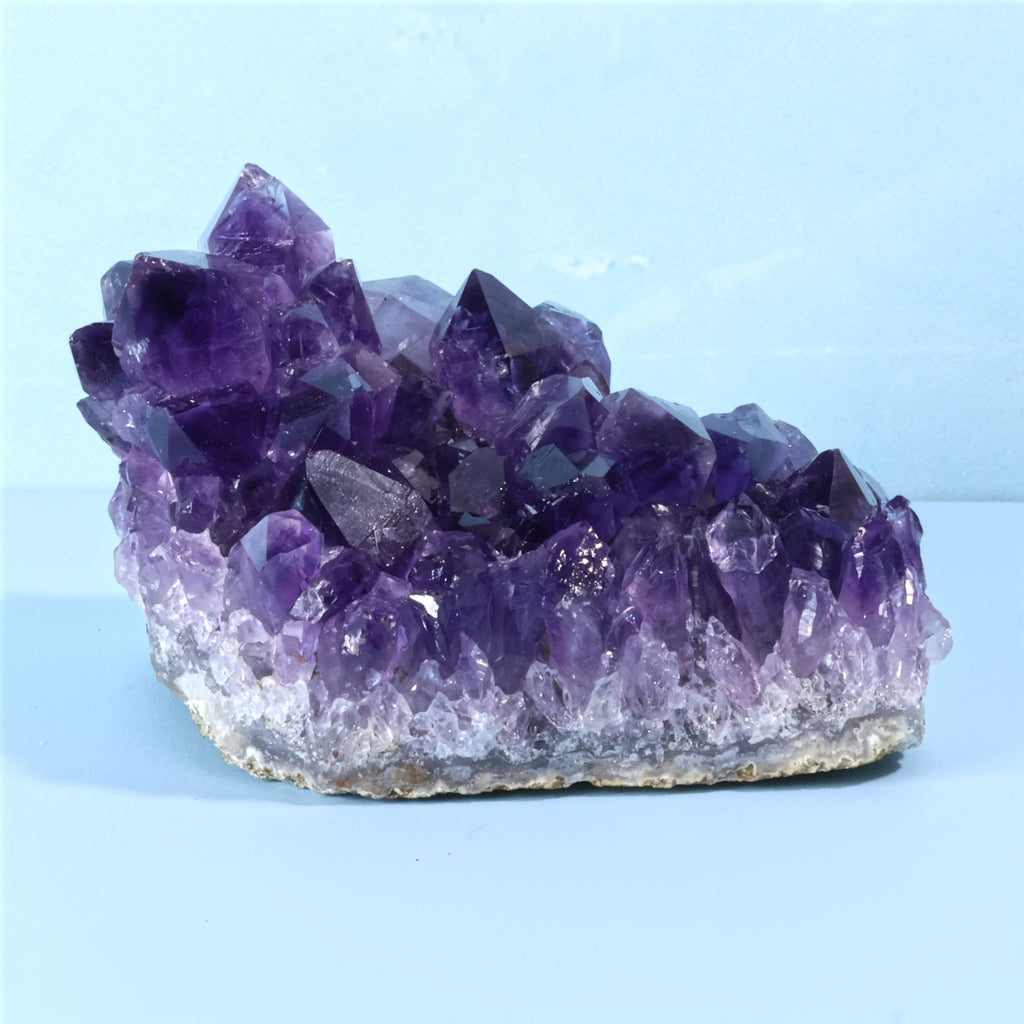 Uruguay Amethyst crystal cluster on a light blue background