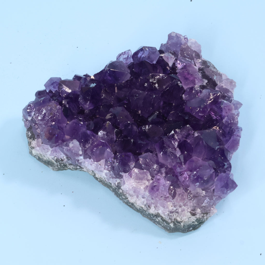 Amethyst crystal cluster on a light blue background
