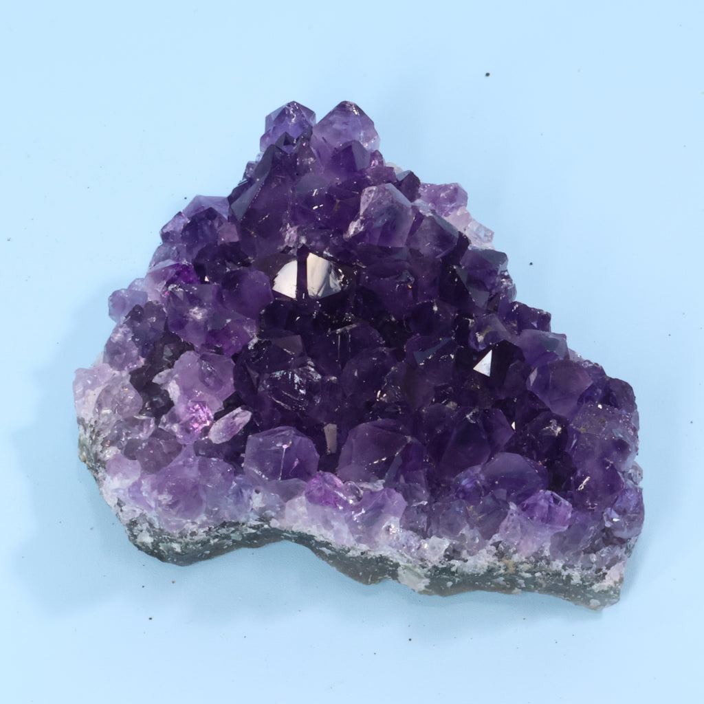 Amethyst crystal cluster on a light blue background