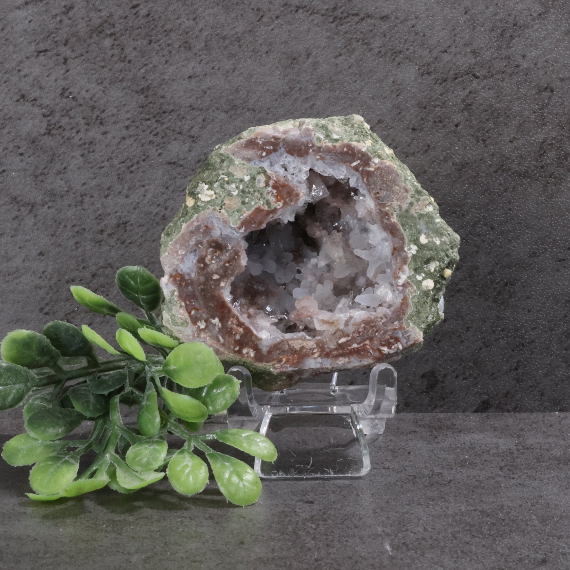 Geode on a stand with green leaves against a dark background